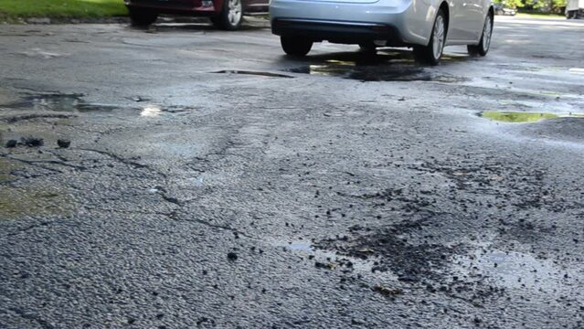 Car hits pothole in road, splashes water. Car runs into bad road conditions