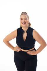 A young Caucasian plus-size model in black sportswear stands on white background, copy space - 792788941