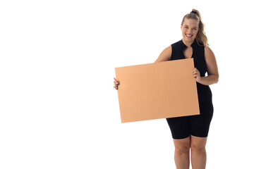 A young Caucasian plus size model holds blank sign, smiling on a white background, copy space