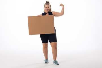 A Caucasian plus-size model with white background holds a sign, copy space