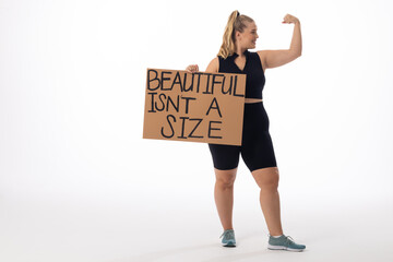 Caucasian plus size young female model holds poster, flexes arm on white background