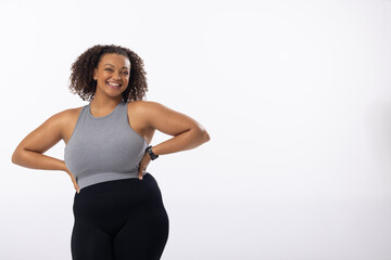 Biracial plus size female model with hands on hips, white background, copy space