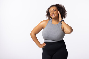 A biracial plus size model with curly hair laughs on white background, copy space