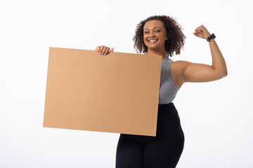 A biracial young female plus size model flexes her arm on white background, copy space