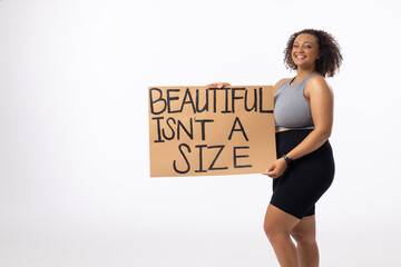 A biracial plus size model holds body positivity poster on a white background, copy space