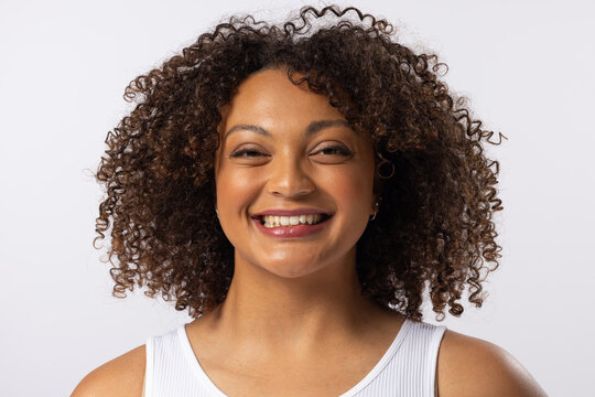 A biracial young plus size model smiles, wearing white tank top