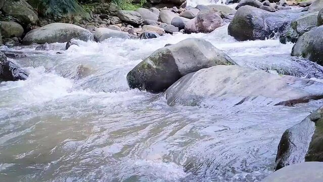 Water flowing over river rocks near mountain at coffe and eatery called kopi tepi hutan, sentul bogor, west java.