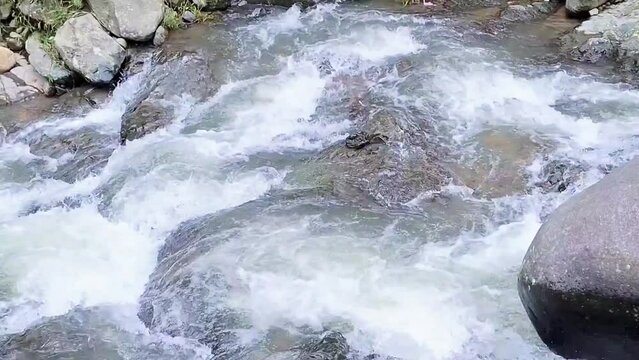 Water flowing over river rocks near mountain at coffe and eatery called kopi tepi hutan, sentul bogor, west java.