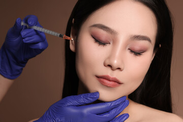 Woman getting facial injection on brown background