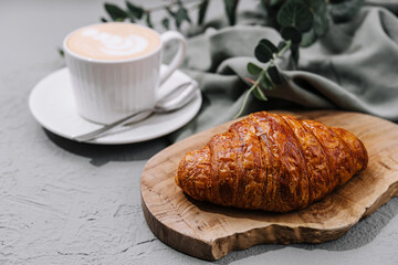Fresh croissant and latte on rustic table