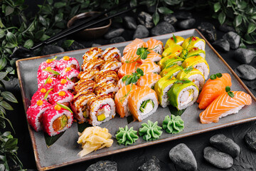 Assorted sushi and rolls platter on stone background