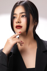 Young sexy fashionable Asian woman wearing black jacket shows perfect red lips in studio. Cosmetics, femininity.