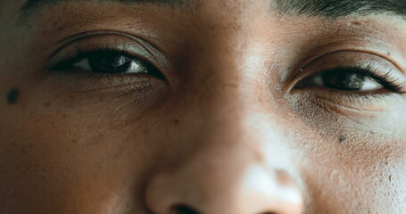 One Young black woman eyes in macro close-up, facial detail of 20s person gazing at camera with...