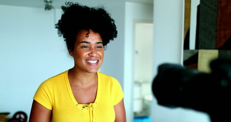 One young black woman speaking in front of camera giving testimony for online channel. 20s female vlogger creating video post engaged with new media