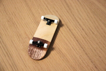 Wooden fingerboard at the ramp on table, close up. Mini skateboard, small skateboard deck © Tom