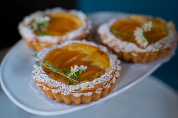 Almond peach tart is stuffed with peach and topped with slices almond on a table. Summer homemade sweet pastries