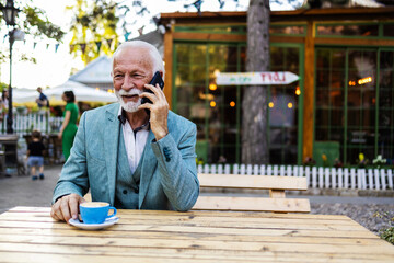 Phone call, business man and laughing in city, cafe or town while talking with contact. Businessman talking on mobile phone while having a cup of coffee.
