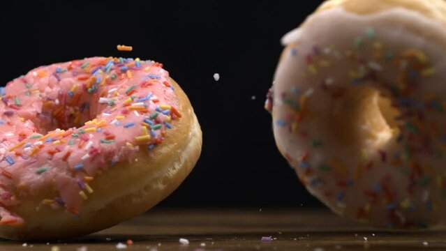 Large donuts falling into table surface in super slow-motion at black background. Three carb food snacks in macro captured with a high-speed camera at 800s