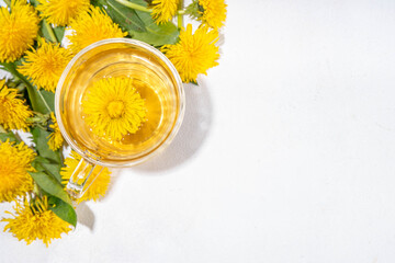 Dandelions plant herbal flower tea. Transparent glass cup and teapot with golden hot tea drink, on white background with dandelion flowers and leaves