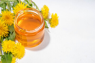 Dandelion jam, jelly confiture in a jar with fresh dandelion flowers on a white table background