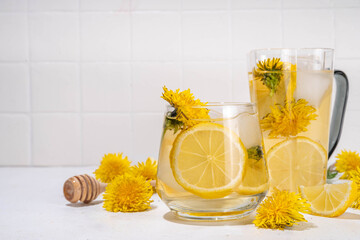 Dandelions cold iced tea or lemonade. Plant herbal flower drink with dandelions flowers and roots, lemon and syrup, on white table background copy space
