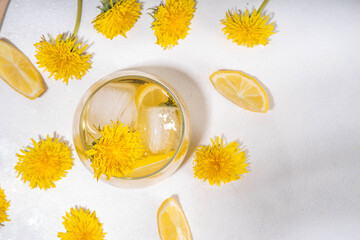 Dandelions cold iced tea or lemonade. Plant herbal flower drink with dandelions flowers and roots, lemon and syrup, on white table background copy space