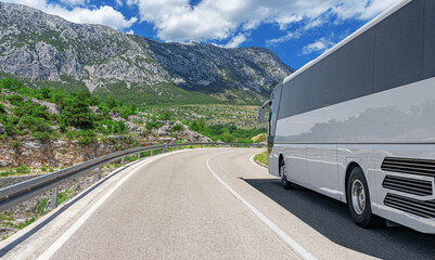A white bus is descending through a cloudcovered ecoregion, surrounded by lush trees and plants on...
