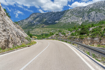 Fototapeta premium Country road with rocky mountains in the background.