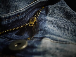Close-up of a denim zipper with a zipper pull, unzipped.
