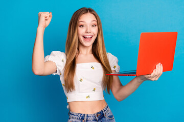 Photo of excited girl use netbook raise fists isolated blue color background