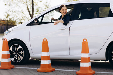 Woman sits in car , driving back and looking at the cones set up close to car