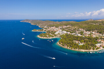 Hvar, Croatia: Aerial view of the coast lined with hotel and beach resort near the medeival Hvar old town in Croatia on a sunny summer day - obrazy, fototapety, plakaty