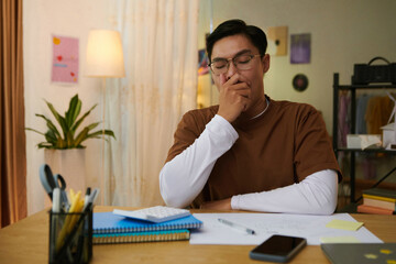 High school student bored of doing homework, he is yawning and covering mouth with hand