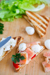 fried toast with salmon, cream cheese, salad, on a wooden table
