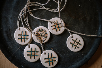 Valmiera, Latvia - August 10, 2023 - Ceramic pendants with symbols and patterns on a twine string,...