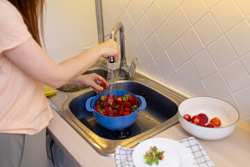 girl in the kitchen washes strawberries