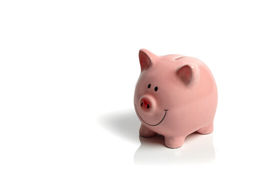 Piggy bank isolated on a white background; happy, pink piggy bank on a white background; concept image money saving, economy, cost of living with copy space.