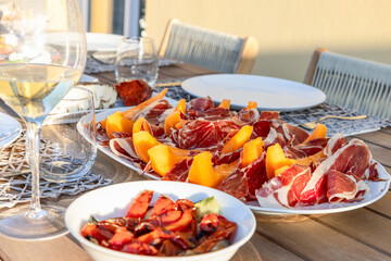 A terrace table in Italy graced with the classic pairing of sweet melon and savory Prosciutto under...