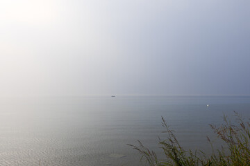 A solitary swan and a lone fishing boat are adrift on Lake Garda vast waters, encapsulated by the...