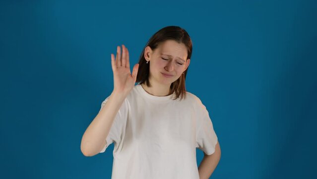 Lady shows Stop sign using hand during argument on blue background. Lady hand serves as visual barrier against torrent of words exchanging slow motion