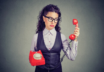Young business woman looking at a red phone with a suspicious expression