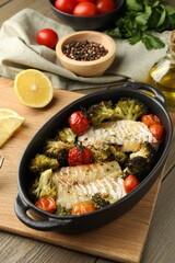 Tasty cod cooked with vegetables on wooden table