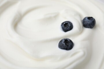 Tasty yogurt with blueberries as background, closeup. Space for text