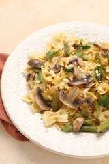 Vegetarian pasta with mushrooms, parsley, string beans and cheese on orange textured table, closeup