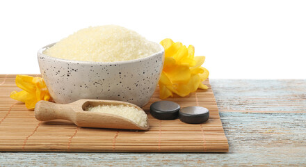 Natural sea salt in bowl, flowers, spa stones and scoop on wooden table against white background