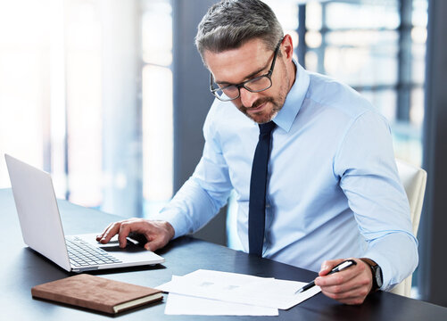 Laptop, paper and businessman with thinking in office for investment, portfolio review and update. Professional person, mature broker and tech with documents for stock market, analysis and planning