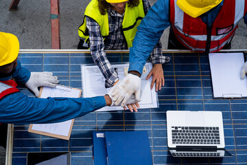 Three construction workers shake hands while looking at a laptop. Scene is professional and...