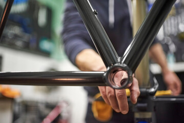 Unrecognizable person assembling a bicycle in his bike shop as part of a maintenance service. Real...