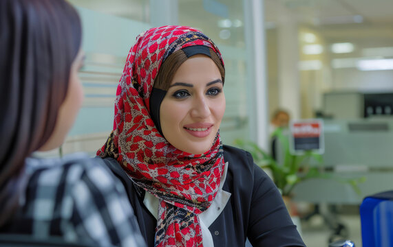 An approachable Arab businesswoman chats with a job candidate during an interview in the office, highlighting her friendly demeanor and expertise in evaluating candidates' suitability for roles.