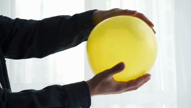 A yellow inflatable balloon is in the hands of a guy.
Yellow inflatable ball